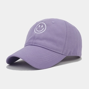 Close-up of white smiling face embroidery on lavender cotton baseball cap fabric