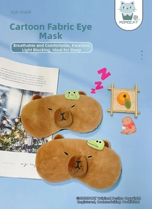 Detail view of plush Capybara sleep eye masks with small green frog and crocodile decorations