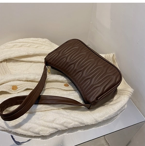 Detail view of dark brown underarm bag with unique wavy quilted texture and wide strap