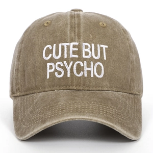 Close-up of 'CUTE BUT PSYCHO' white embroidery on washed cotton baseball cap