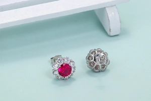 Macro shot of silver studs with round ruby centers and clear stones on white wood