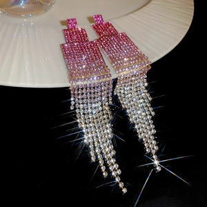 Détail macro de boucles d'oreilles à pompons en strass dégradés sur une assiette en céramique