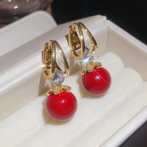 Détail de boucles d'oreilles boules rouges avec monture dorée et zircon sur un coffret