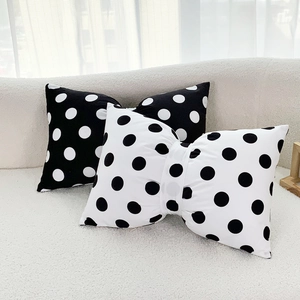 Bow-shaped velvet pillows with polka dots on a sofa in a minimalist living room setting