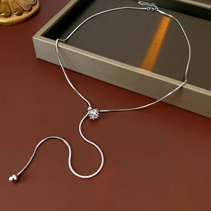 Detail of silver snake chain necklace with sliding cubic zirconia buckle and tassel chains