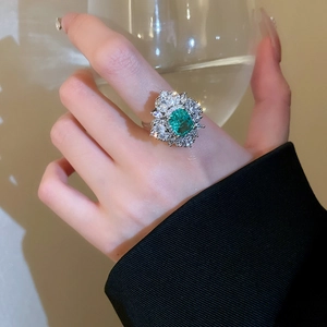 Macro detail of a vintage emerald ring with layered diamonds on a silver band