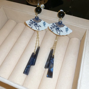 Détail de boucles d'oreilles éventail chinois avec motif bambou et glands marbrés