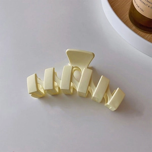 Détail d'une pince à cheveux crème en forme de vague avec une texture mate élégante