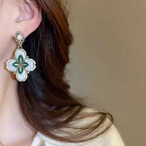 Gros plan de boucles d'oreilles fleurs vintage avec bords dorés et émail blanc sur modèle