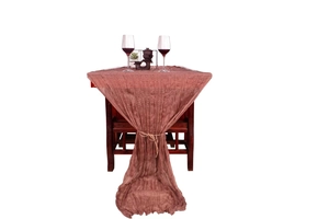 Close-up of pink-brown crinkled cheesecloth table runner tied with rustic hemp rope