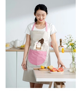 Detail of beige waterproof apron with pink straps and cute cartoon girl graphic in kitchen