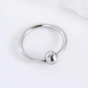 Minimalist silver stainless steel circular piercing ring with round bead on white background