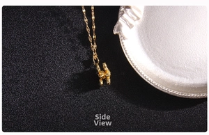 Detailed side view of golden double-C clover pendant with shimmering micro-pave zircons