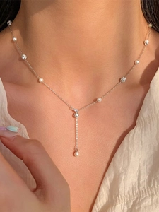 Detail of silver Y-shaped stainless steel necklace with faux pearls and zircons on neck