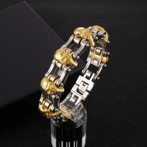 Detail of two-tone stainless steel biker chain bracelet with golden skull links