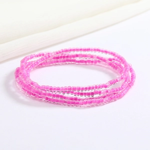 Macro shot of multi-layer pink glass seed bead waist chain on white fabric background