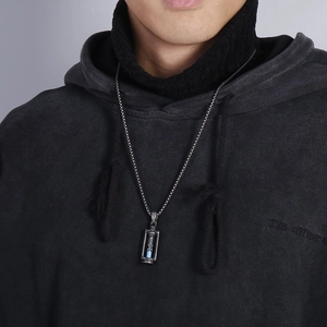 Vintage stainless steel hourglass pendant with blue sand on a black hoodie model