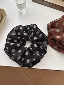 Detail of brown and black chiffon polka dot hair scrunchies with soft pleats on white desk