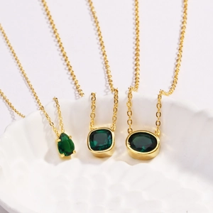 Detailed shot of emerald green crystal pendants on gold chains in various geometric shapes