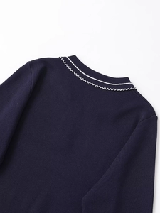 Detail of dark blue knit polo shirt featuring a contrast white scalloped edge on the collar