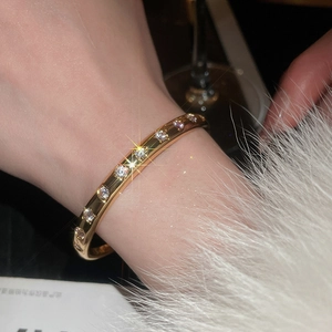 Vue détaillée d'un bracelet doré orné de zircons sur un fond en peluche blanche