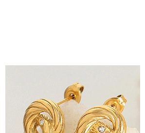 Macro shot of gold knot earrings featuring a twisted design with a clear zircon center