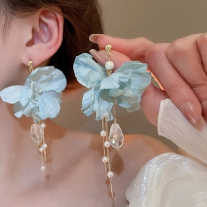 Close-up of blue fabric flower earrings with long pearl tassels and crystal drop charms
