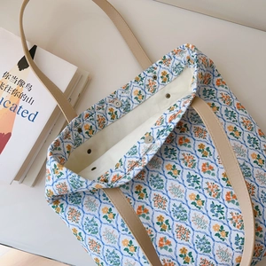 Close-up of floral cotton tote bag with leather straps and magnetic metal closure