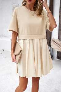 Elegante abito beige a maniche corte con orlo a pieghe mostrato all'aperto