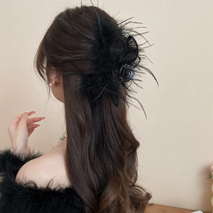 Detail of black feather and mesh bunny ear hair claw clip on model's long hair