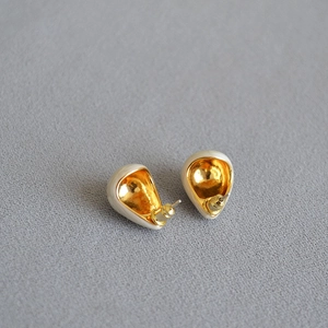 Macro shot of pear-shaped enamel drop earrings with gold-plated hollow design and metal backing