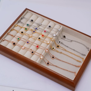 Multi-colored round pendant double-layer titanium steel bracelets displayed on a wooden tray