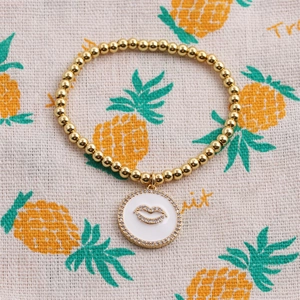 Bracciale a sfere dorate con ciondolo in smalto bianco e motivo a labbra con pavé di strass
