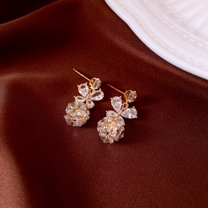 Macro shot of gold star-shaped earrings with zircon and pearls on brown satin