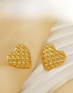 Detailed view of gold heart stud earrings with bubble texture on silk fabric