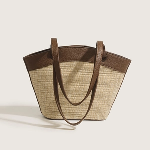 Minimalist straw tote bag with brown leather straps and woven texture for beach vacation