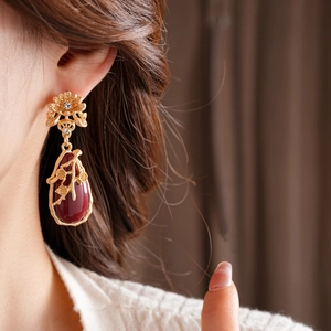 Macro shot of vintage style earrings with burgundy teardrop stones and floral details