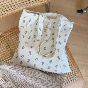 Detail of floral canvas tote bag showing the interior brand label on vintage wicker chair