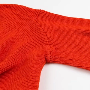 Dettaglio del maglione in maglia arancione-rosso con trama della spalla e cuciture