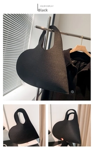 Detail of minimalist black heart-shaped felt handbag hanging on a display hanger