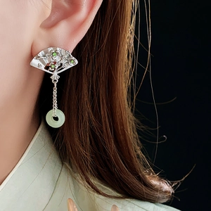 Macro shot of silver fan earrings with green jade rings and sparkling crystal accents