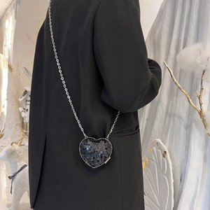 Detailed view of a black heart-shaped sequin mini bag with a slim silver metal chain strap