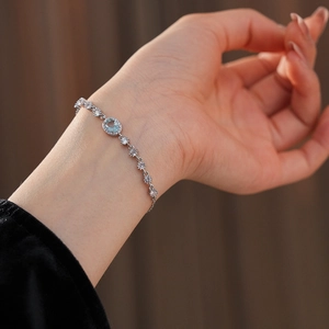 Macro shot of silver zircon flower bracelet with light blue oval stone on woman wrist