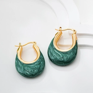 Detailed close-up of U-shaped gold earrings with green marble enamel finish on white background