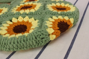 Macro detail of hand-crocheted sunflower handbag showing intricate wool knitting patterns