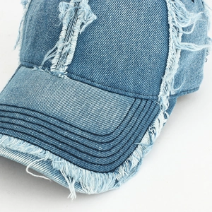 Detailed close-up of distressed denim baseball cap with frayed edges and vintage texture