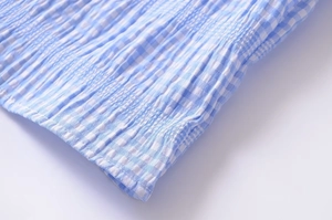Macro detail of blue and white checkered fabric with elegant pleated texture and neat seams