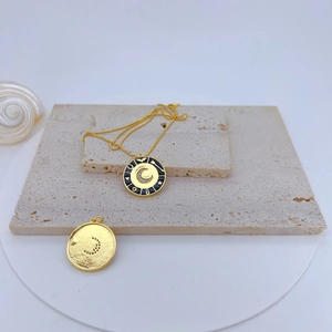 Close-up of gold plated C-letter pendant with black enamel and zircon details