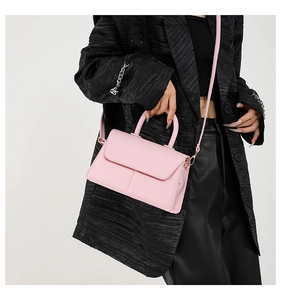 Pink PU leather square handbag with golden hardware worn by a model in a black blazer