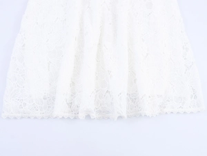 Detailed close-up showing intricate floral lace texture and scalloped hem on white skirt
